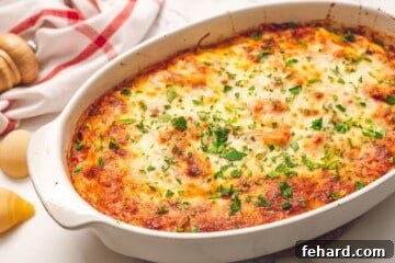 Classic Italian Stuffed Shells 11 Baked Italian Stuffed Shells in white oval baking dish topped with fresh minced parsley, showcasing the golden, bubbly cheese.