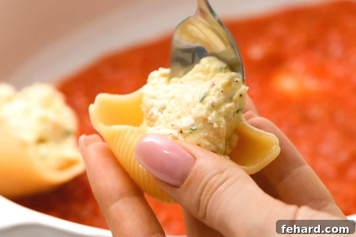Italian Baked Shells Spoon gently stuffing a jumbo pasta shell with creamy ricotta mixture.