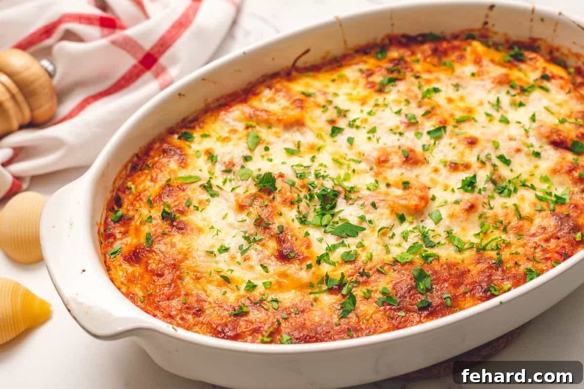 Baked Ricotta Stuffed Shells Beautifully baked Italian Stuffed Shells in a white oval baking dish, garnished with fresh minced parsley, ready to serve.