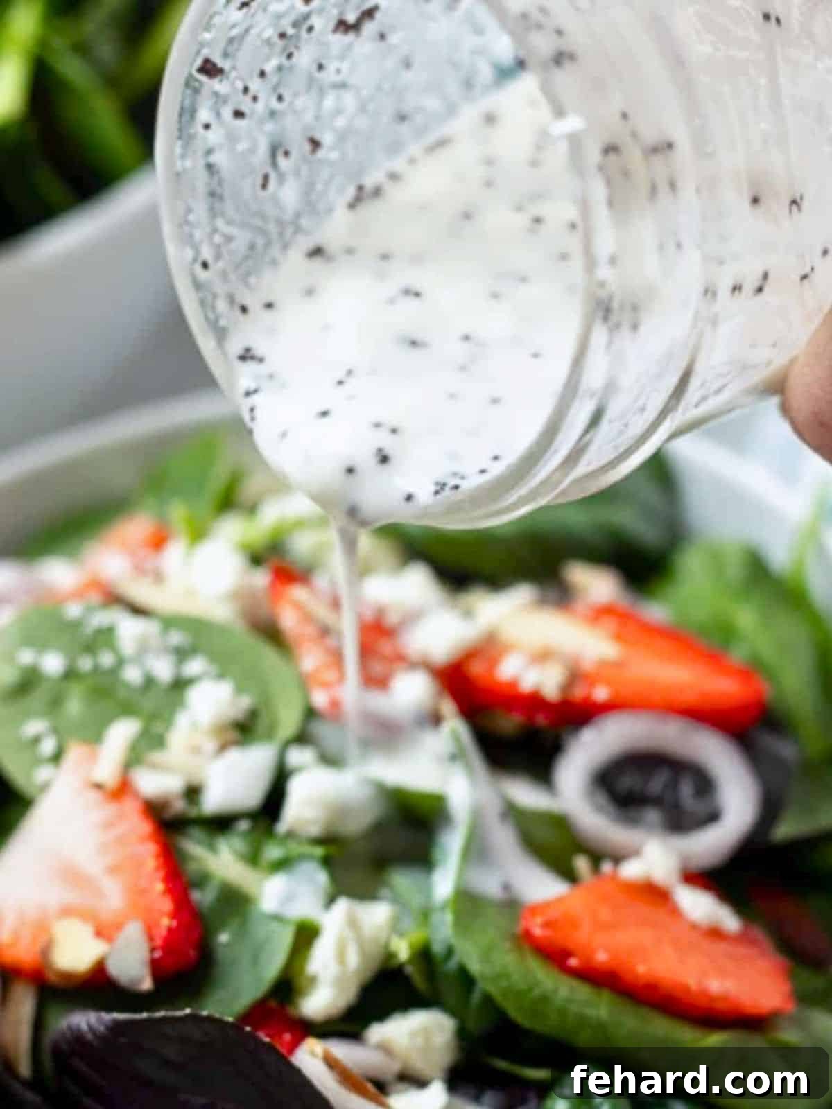 Healthy Greek Yogurt Poppy Seed Dressing Creamy poppy seed yogurt made with greek yogurt being poured over a fresh strawberry spinach salad.