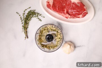 Mini food processor with thyme, garlic, olive oil, processed to form seasoning for steak.