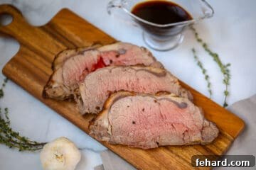 Sliced New York Strip Roast on cutting board with au jus in background.