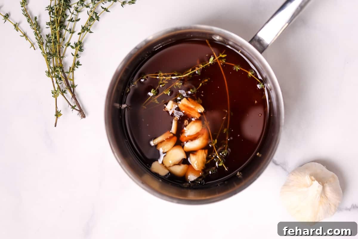 Ingredients for brandy au jus, including beef stock, brandy, garlic, and thyme, simmering in a stock pot.