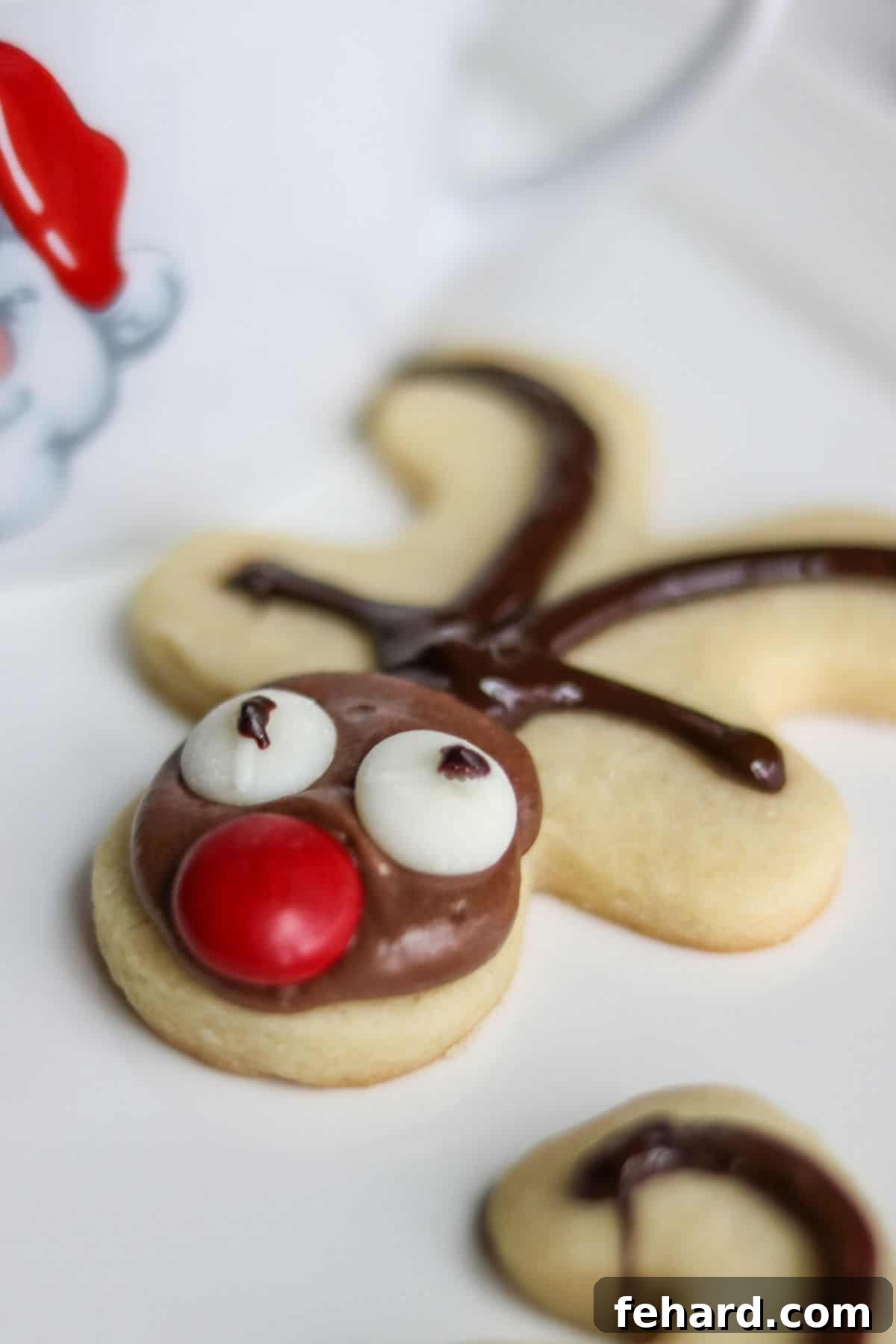An upside-down gingerbread man cookie expertly decorated to resemble a festive reindeer, complete with chocolate antlers, candy eyes, and a bright red nose.