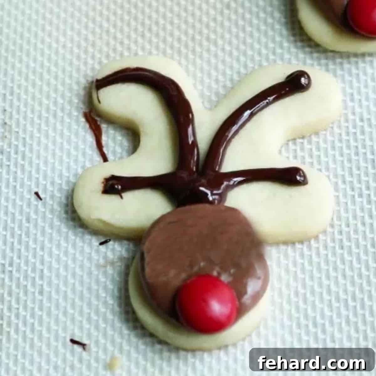 A partially decorated reindeer cookie showing piped chocolate forming the antlers on what was previously the gingerbread man's legs.