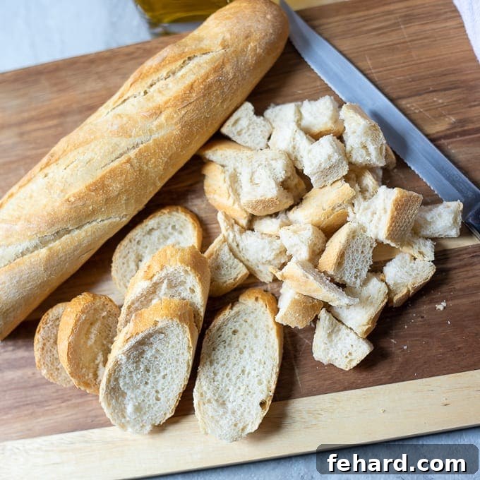 A loaf of fresh Italian bread resting on a wooden cutting board with a knife, ready to be sliced for croutons.