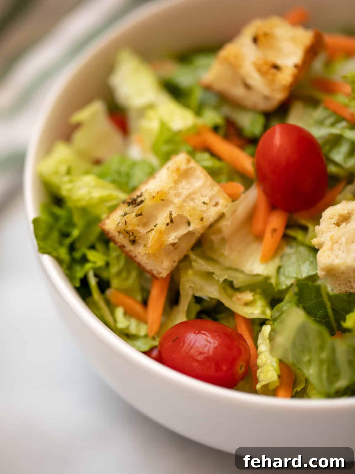 A vibrant tossed salad, generously topped with an abundance of golden, crispy homemade croutons, showcasing their delicious appeal.