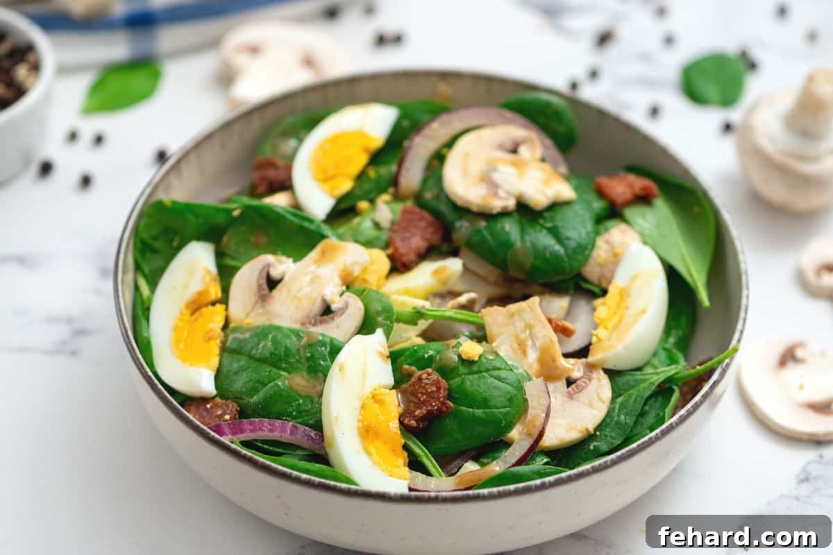 Spinach Salad Recipe with Warm Dressing A close-up of a vibrant spinach salad overflowing with crispy bacon, earthy mushrooms, thinly sliced red onions, and perfectly cooked hard-boiled eggs, ready to be dressed.