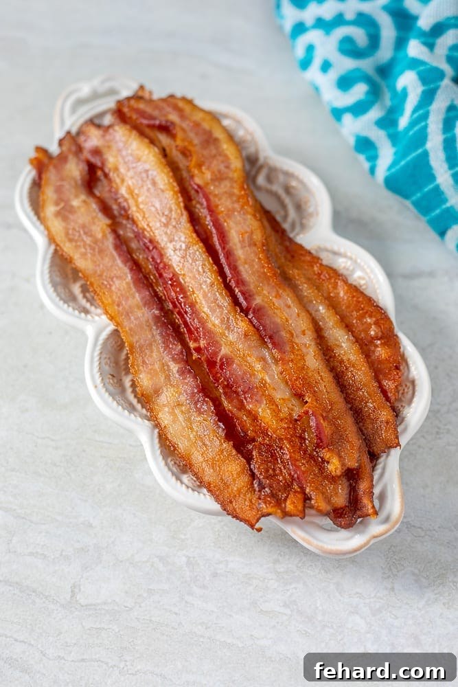 Perfectly baked bacon on a pristine white serving platter, garnished slightly.