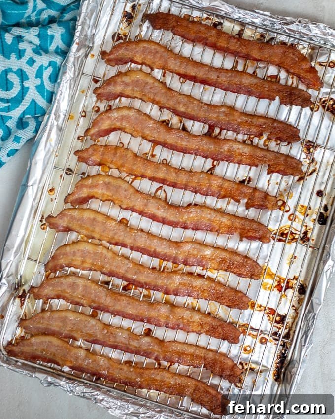 Crispy baked bacon strips on a baking sheet with a wire rack, fresh from the oven.