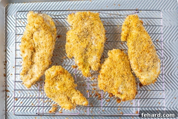 Breaded Chicken Cutlets neatly arranged on a baking rack over a sheet pan.