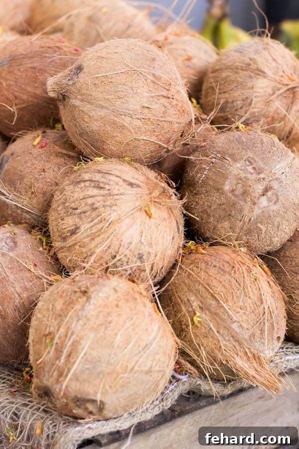 A closeup of a pile of fresh coconuts on a wooden table. 