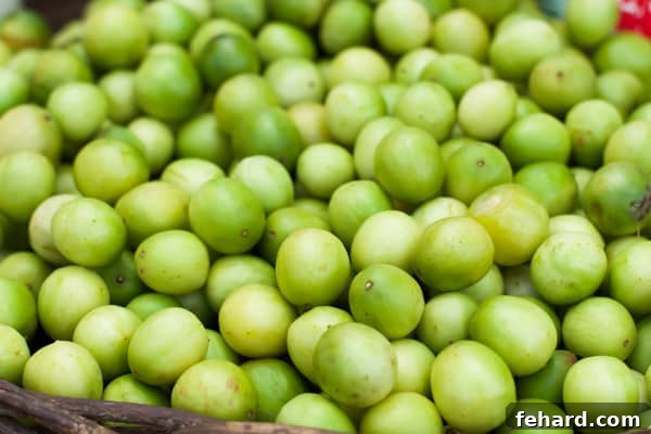 A closeup of a basket of small, green, round  umbu fruit. 