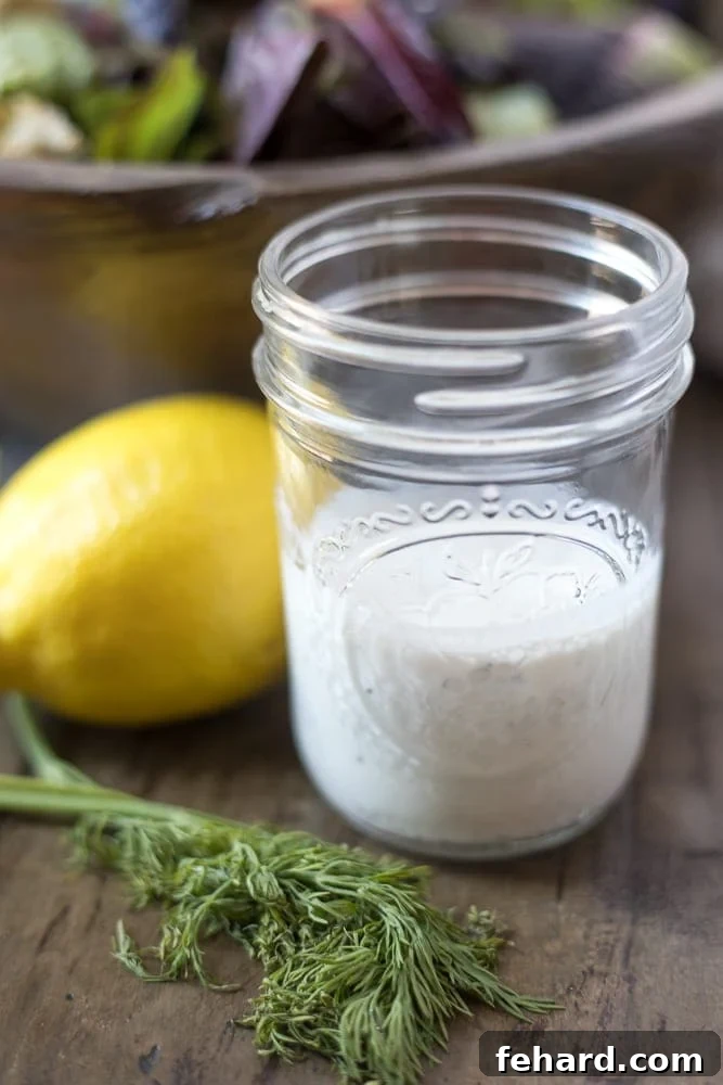Homemade Ranch Dressing A glass jar filled with luscious homemade ranch dressing, with a vibrant tossed salad out of focus in the background, suggesting its perfect use.