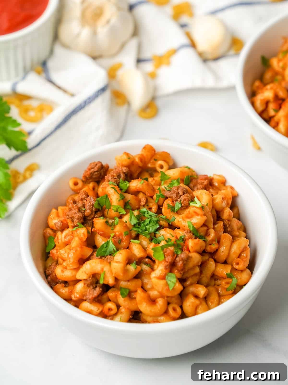 Instant Pot Hamburger Helper Instant Pot Hamburger Helper made with elbow noodles, ground beef, and a homemade sauce served in white bowl topped with parsley.