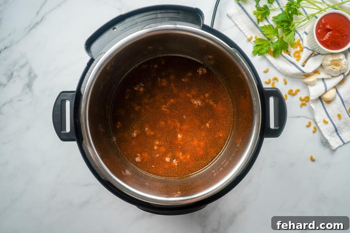 Homemade Hamburger Helper Instant Pot. Beef Broth poured into inner pot on top of ground beef.