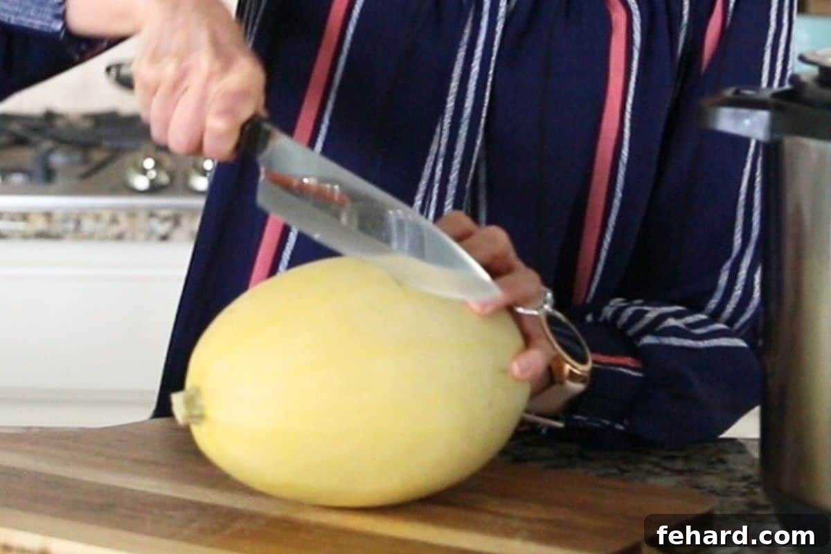 Spaghetti Squash Instant Pot Recipe Knife running widthwise across a spaghetti squash to cut in half.