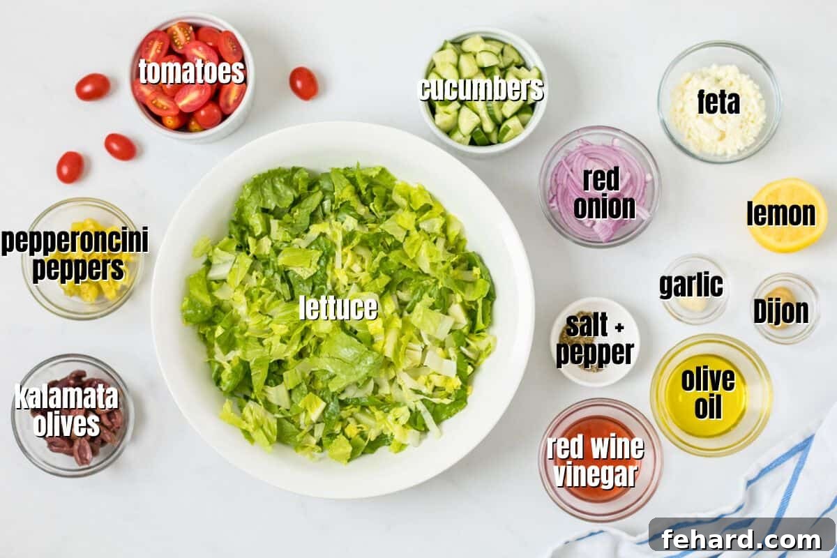 Fresh Ingredients for Greek Salad Panera Copycat A flat lay image of all the fresh ingredients for Panera's Greek Salad neatly arranged on a counter, including romaine lettuce, cucumbers, tomatoes, red onion, kalamata olives, pepperoncini peppers, feta cheese, and ingredients for the Greek dressing like olive oil, red wine vinegar, lemon, garlic, and oregano.