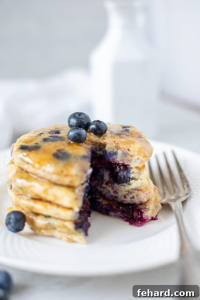 Eggless Pancakes with blueberries on white plate with bite cut out.