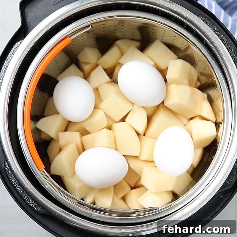 Instant Pot Potato Salad Recipe Setup A clear visual of cubed russet potatoes and whole large eggs expertly arranged on a metal steamer trivet inside the Instant Pot's inner pot, ready for the lid to be sealed and cooking to begin.