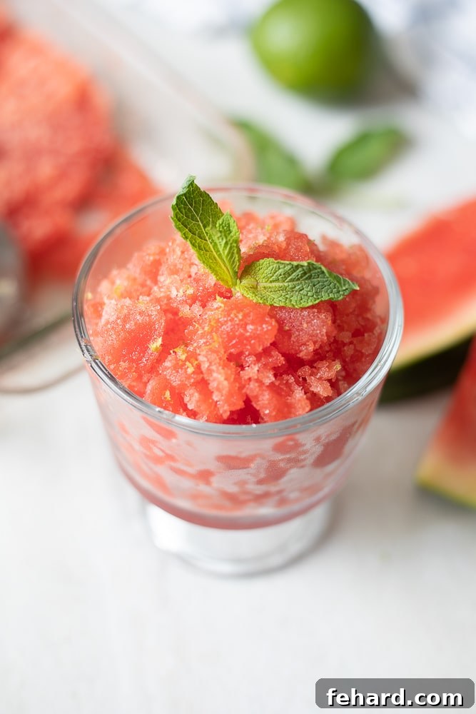 Watermelon Granita in a glass bowl, garnished with fresh mint leaves and a sprinkle of mint sugar.