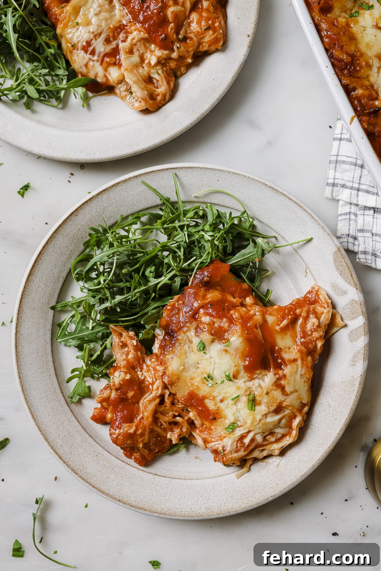 A serving of lasagna rolls on a plate with salad greens. 