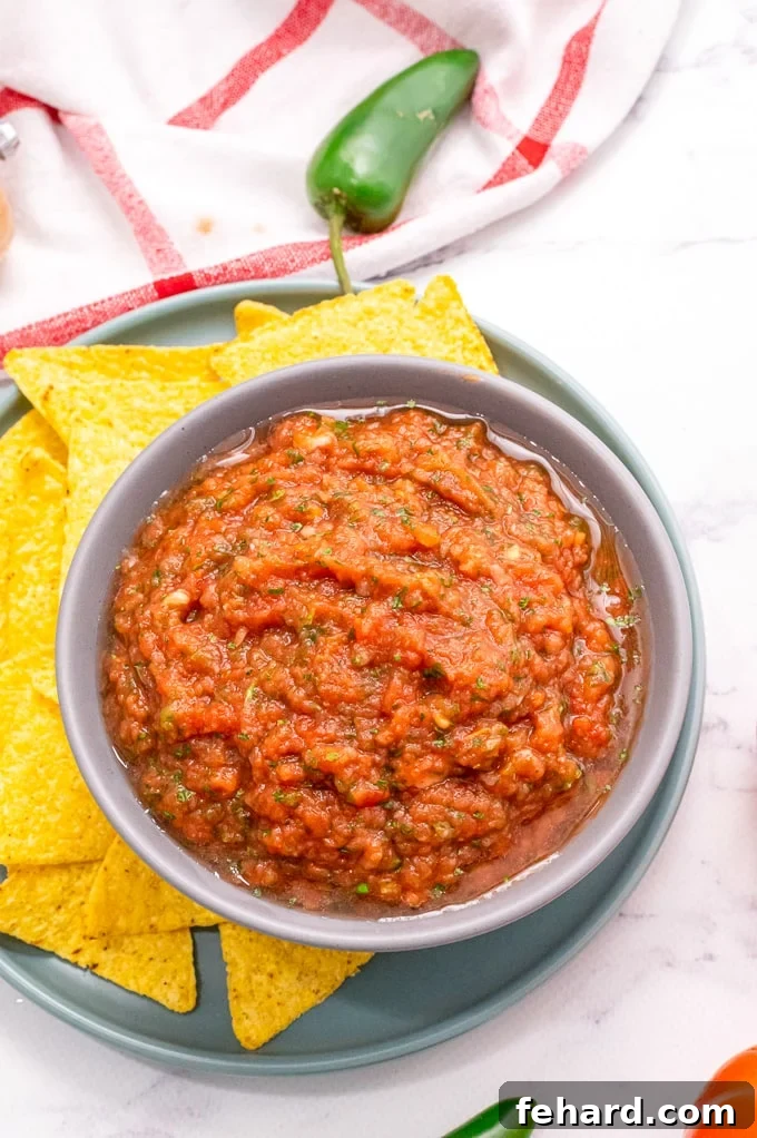 Speedy Blender Salsa 2 Salsa in white dish with chip dipping into the fresh salsa, highlighting the perfect texture