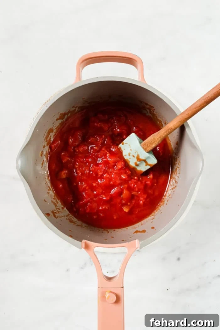 The Secret to Perfect Homemade Tomato Sauce 6 The tomato sauce simmering gently in a covered pan, allowing the flavors to meld and develop a rich taste.