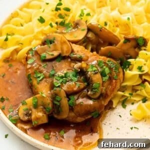 Thick-cut juicy Instant Pot pork chop served with mushroom gravy over egg noodles.