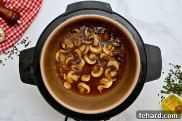 Sauteed mushrooms in inner pot after being deglazed with beef stock.