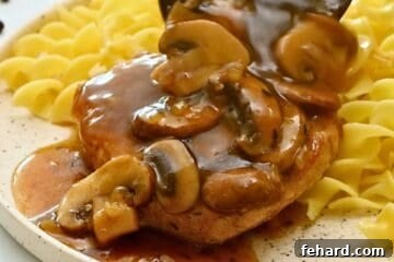Mushroom gravy being poured over pressure cooked pork chop with buttered noodles.