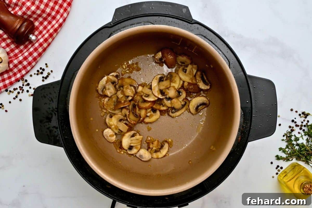 Sautéed mushrooms and onions inside the Instant Pot inner pot, forming the base of the gravy.