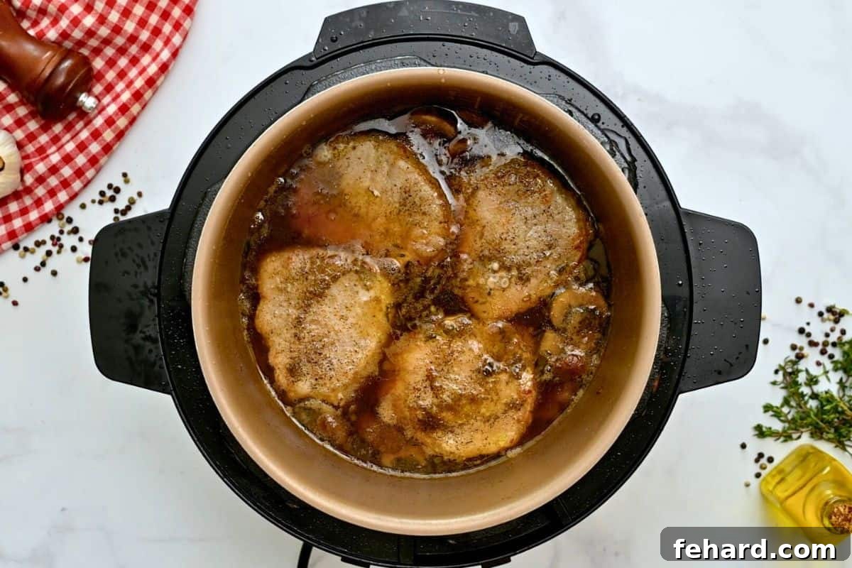 Pressure cooked pork chops simmering in a rich gravy inside the Instant Pot.