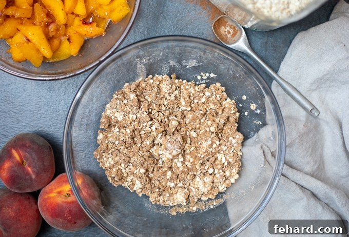Close-up of the crumbly peach crisp topping mixture in a mixing bowl, featuring oats, flour, sugar, and butter, ready to be sprinkled.