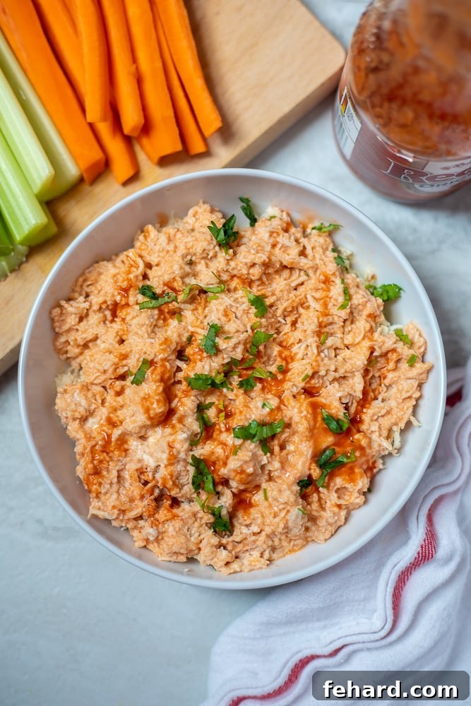 Instant Pot Buffalo Chicken Shredded Instant Pot Buffalo Chicken in a white dish, garnished with fresh carrots and celery sticks