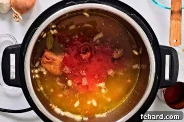 Ingredients for ham and bean soup layered in inner pot of Instant Pot.