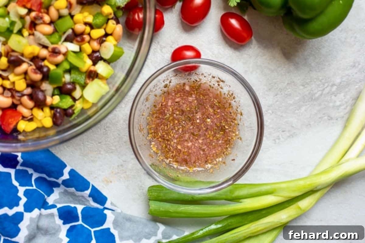 Easy Black-Eyed Pea Salsa Dressing The zesty dressing for black eyed pea Texas Caviar is shown in a large mixing bowl, with fresh green onions and cilantro placed nearby, ready to be added to the salad.