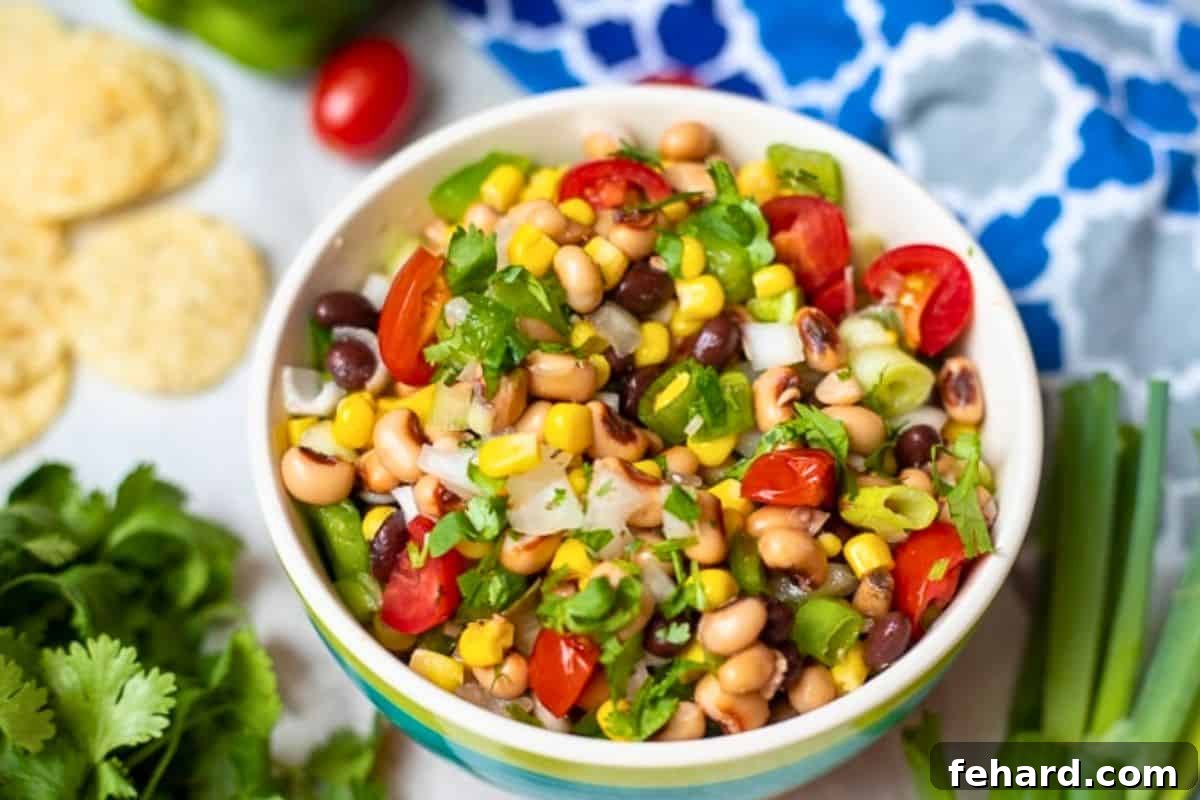 Cowboy Caviar Ready to Serve A beautifully presented bowl of Texas Caviar, brimming with black-eyed peas, black beans, corn, and colorful tomatoes, sits ready for serving, garnished with fresh cilantro and green onions.