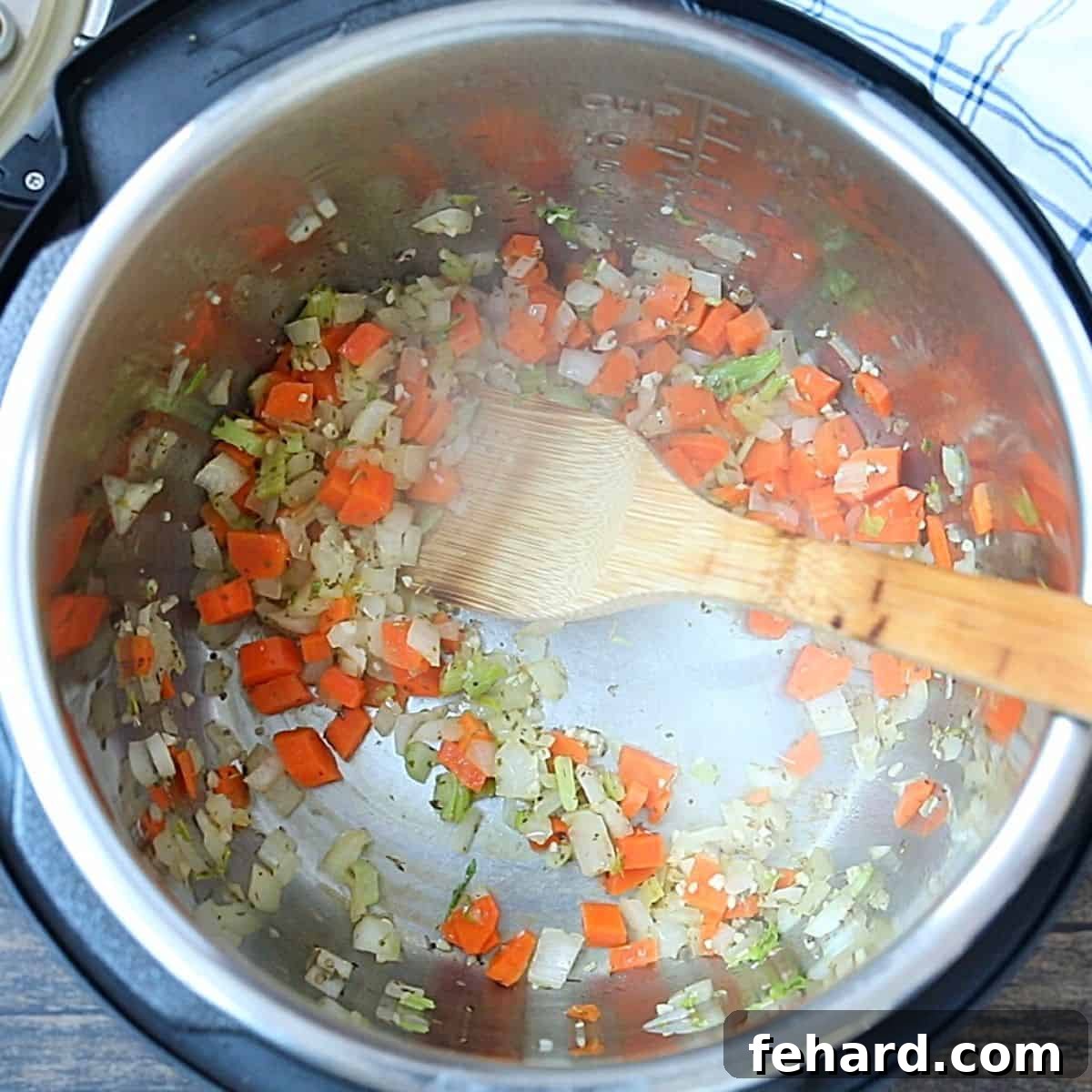 Finely chopped onions, celery, and carrots sautéing in the stainless steel inner pot of an Instant Pot, creating the aromatic base for the minestrone.