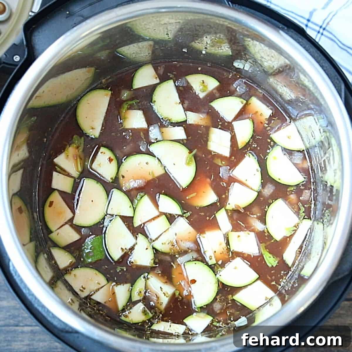 All minestrone ingredients, including broth, vegetables, beans, and pasta, layered in the Instant Pot inner pot before pressure cooking.