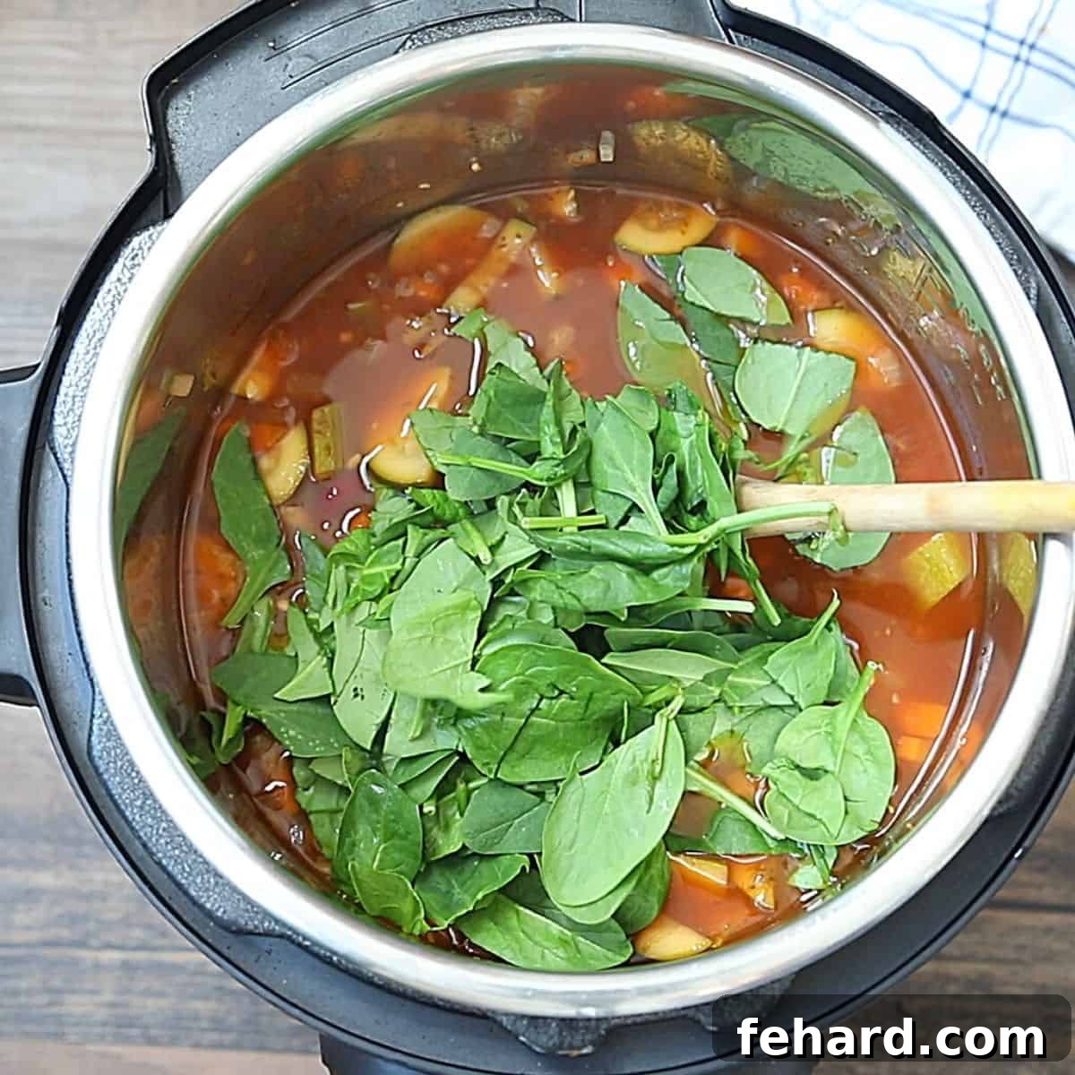 Fresh baby spinach leaves are stirred into the hot, cooked minestrone soup in the Instant Pot, just before serving.