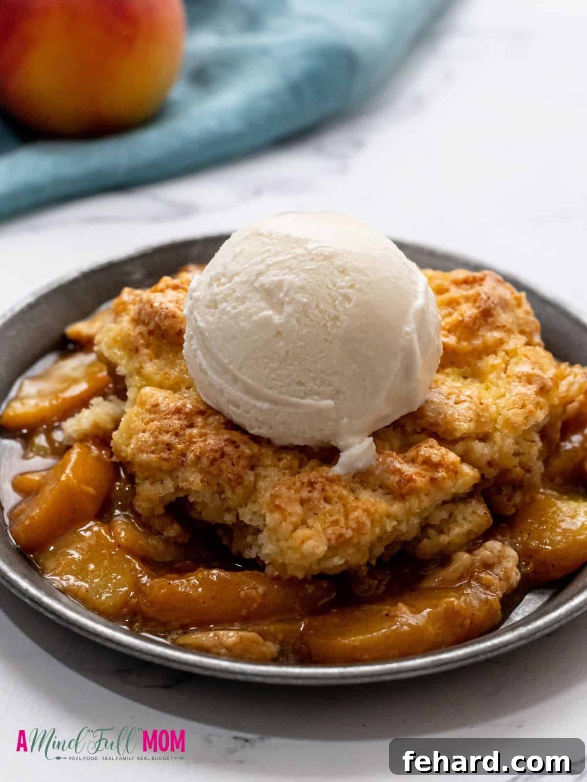 Peach Cobbler dished out on silver plate and topped with a scoop of vanilla ice cream. 