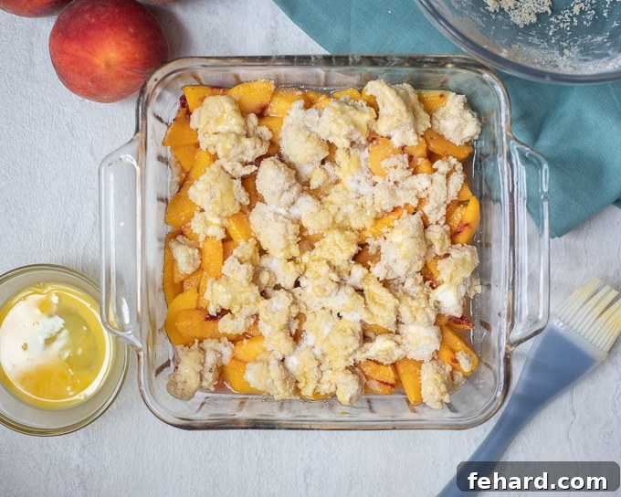 Biscuit Cobbler Topping spread over peaches in baking dish. 