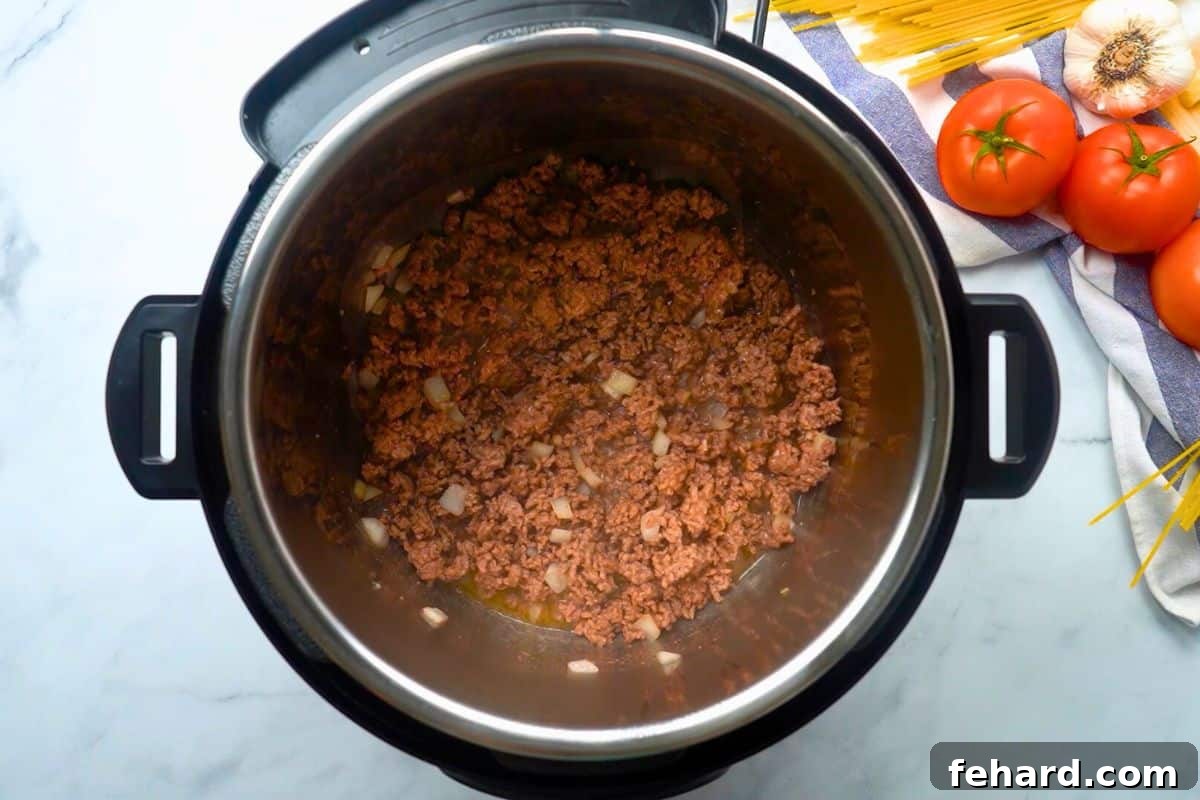 Sautéed ground beef and minced onions cooking in the Instant Pot, forming the delicious base of the spaghetti sauce.