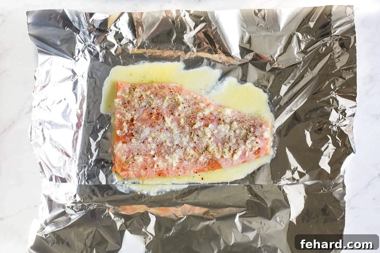 Salmon on a baking sheet, seasoned with spices over the melted butter mixture.