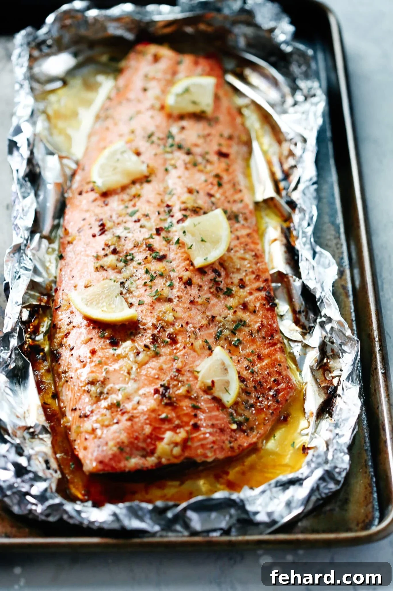 Close-up of perfectly baked salmon fillet with lemon slices and garlic butter sauce, ready to serve.