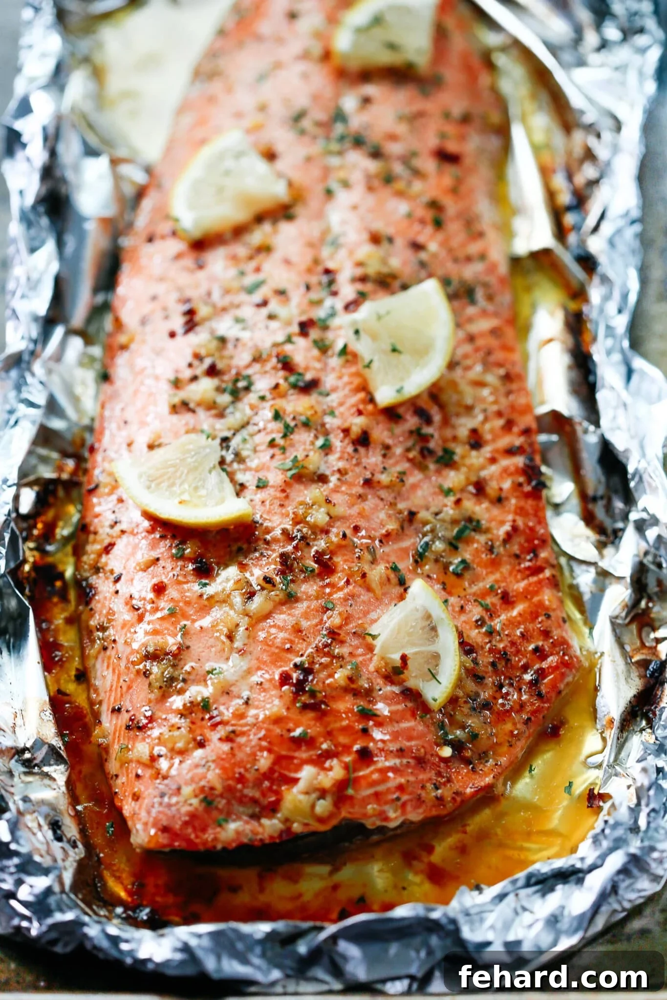 Closeup of cooked baked fish with vibrant lemon slices and a rich garlic butter sauce on top, ready to be served.