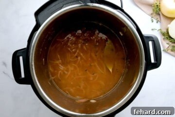 Onions, broth and seasonings layered in inner pot for French Onion Soup before pressure cooking.