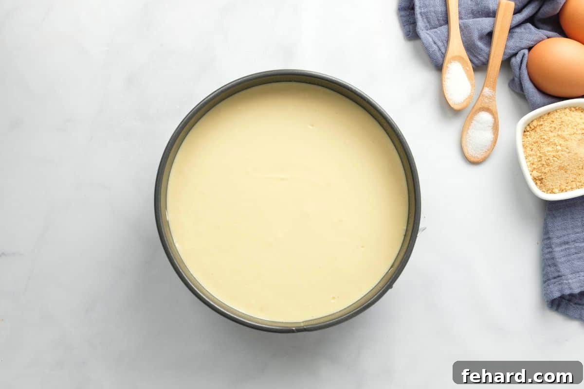Smooth cheesecake batter poured into a 7x3 inch springform pan, resting on top of the graham cracker crust, ready for pressure cooking.