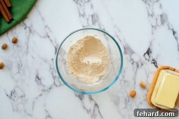 A small mixing bowl containing the whisked dry ingredients for the pumpkin roll cake.